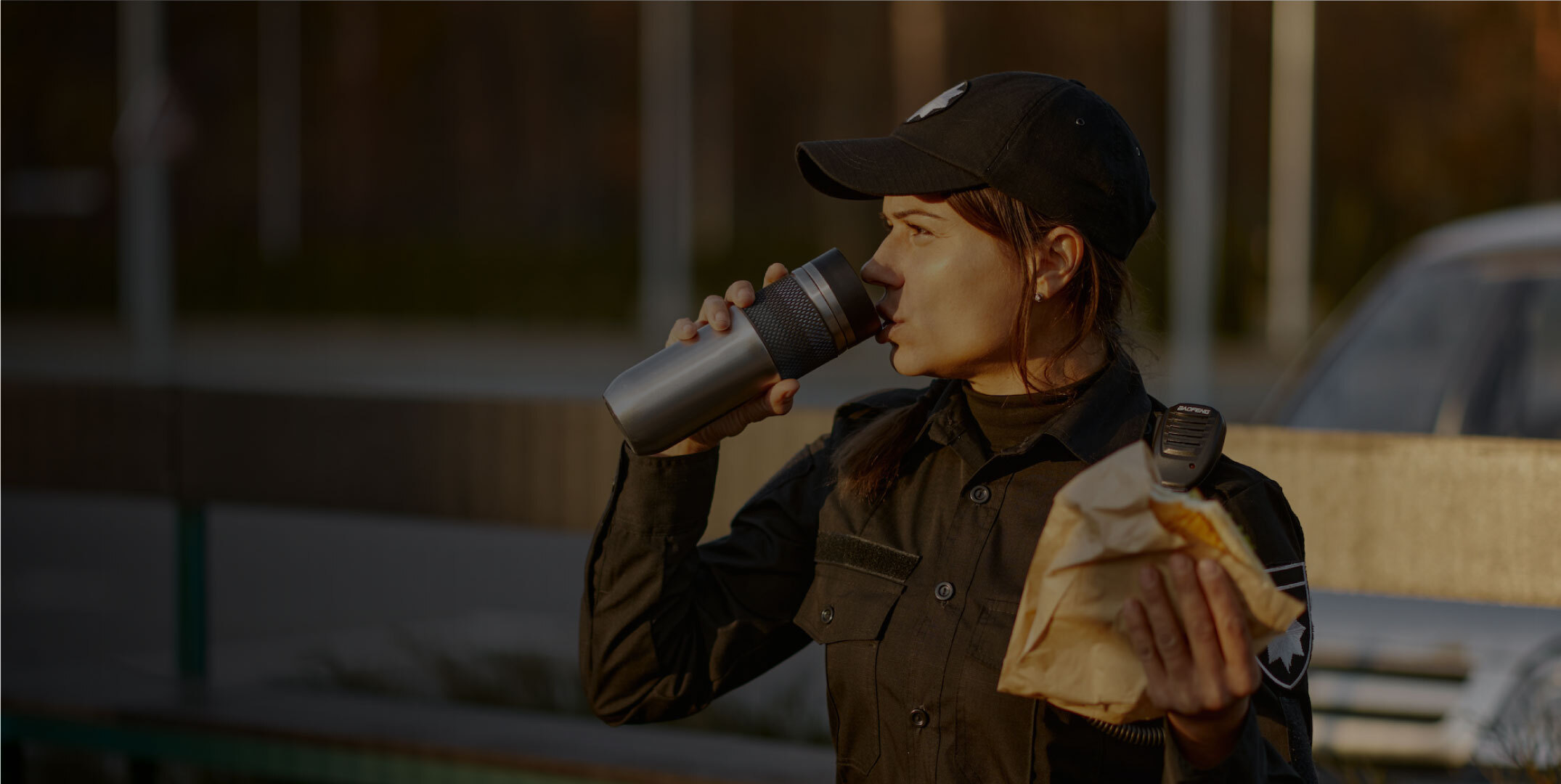 Security guard drinks from a water bottle while holding a sandwich