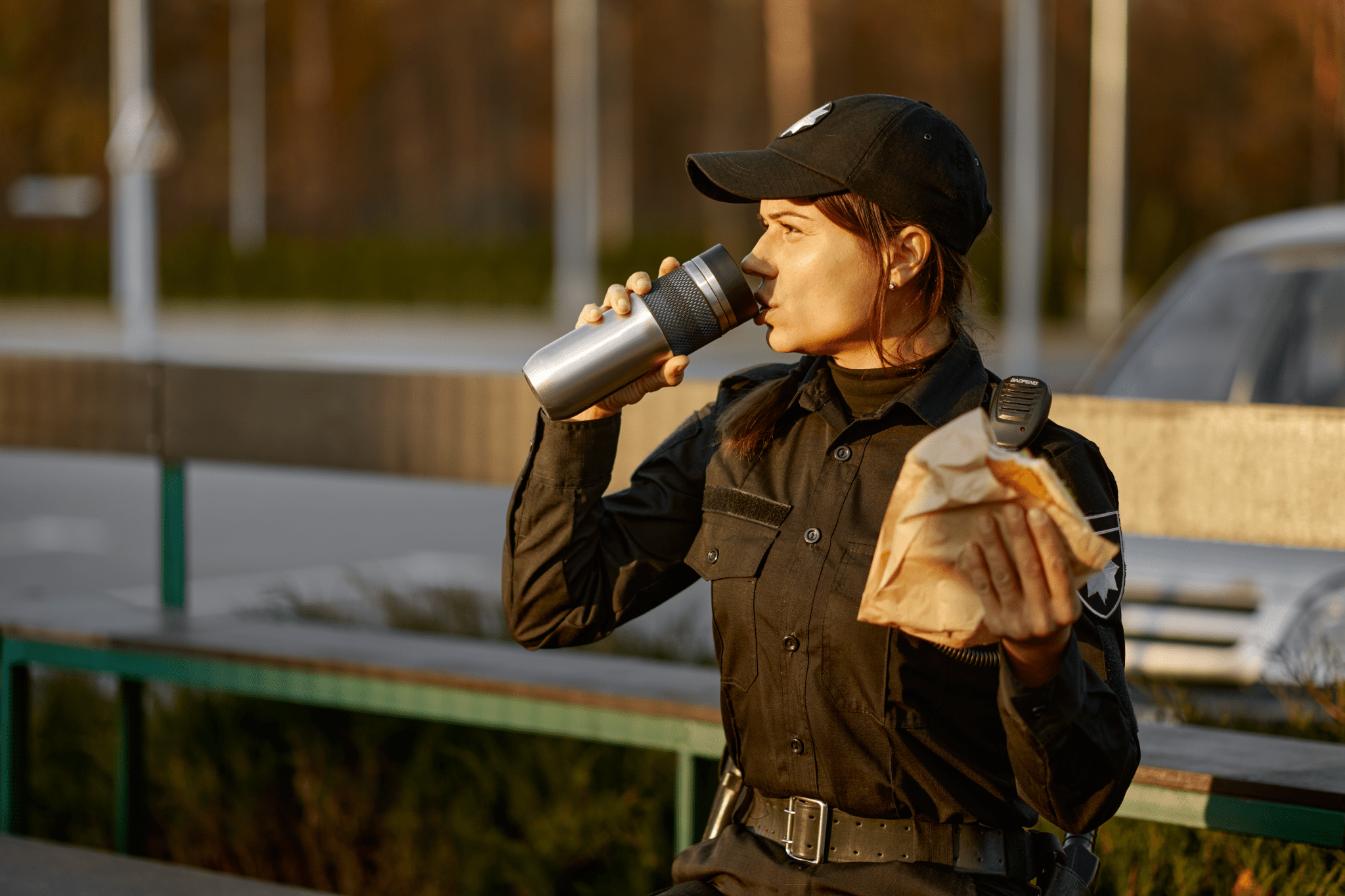 female security guard drinking from her water bottle and holding a brown paper lunch bag